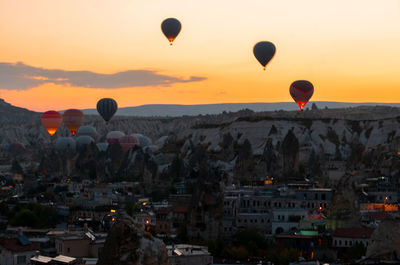 Hot air balloons flying over cityscape during sunset