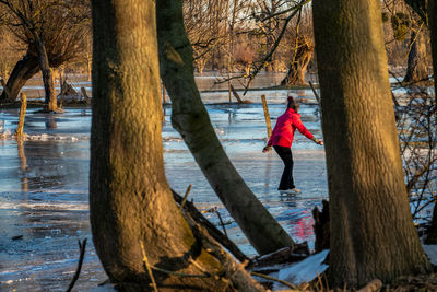 Woman standing by tree trunk during winter