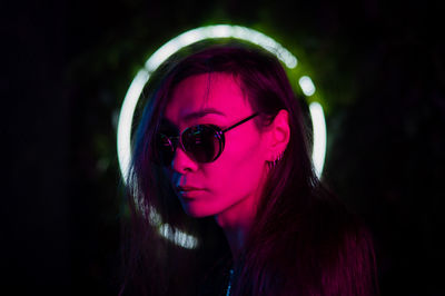 Portrait of young man wearing sunglasses against black background