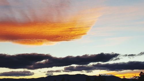 Scenic view of mountains against cloudy sky at sunset