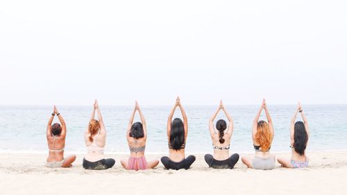 Group of people relaxing on beach against sky