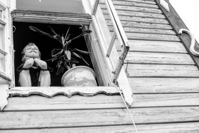 Low angle view of boy sitting on window sill