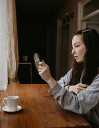 Young woman using mobile phone while sitting on table