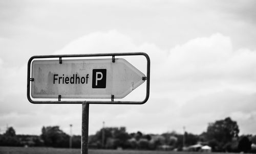 Close-up of road sign against sky