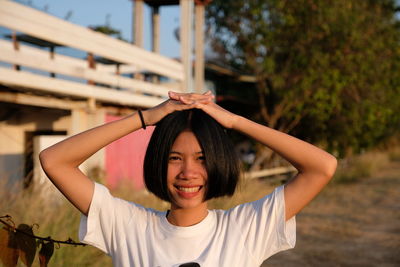 Portrait of smiling young woman against tree