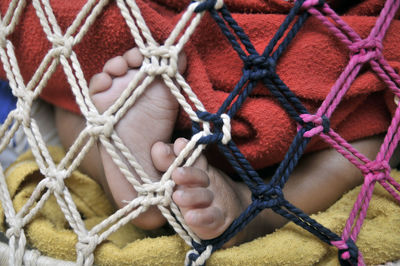 Low section of baby by rope on bed at home
