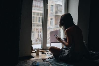 Woman reading book while sitting on floor at home