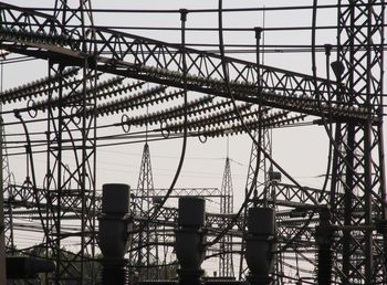 Low angle view of silhouette power lines of an electricity plant against sky