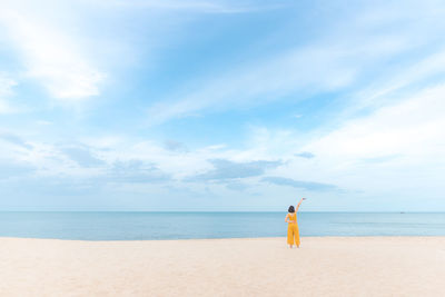Rear view of woman at beach against sky