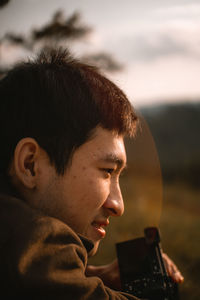 Close-up of man looking away against sky