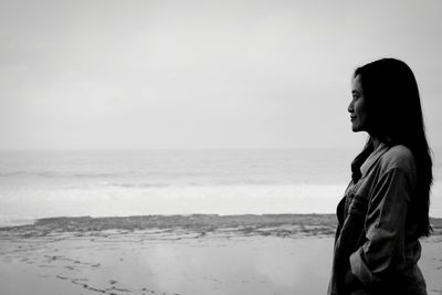 Full length of woman standing at beach against sky