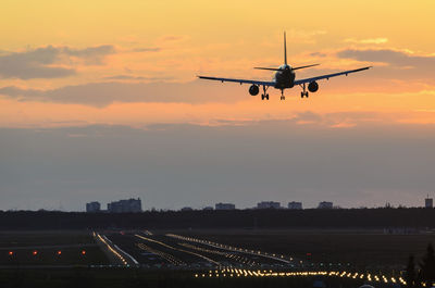 Airplane flying in sky at sunset