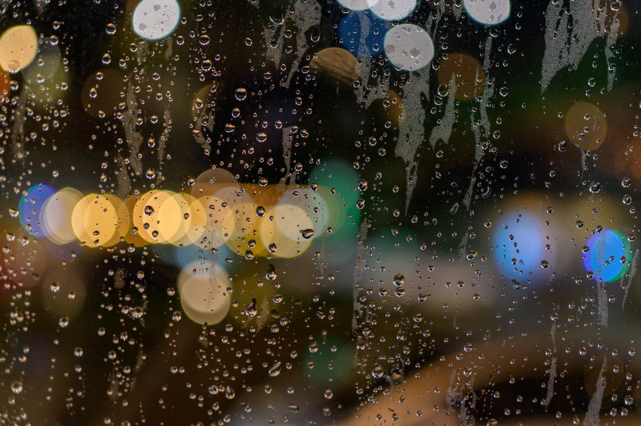 CLOSE-UP OF WET GLASS WINDOW AT NIGHT