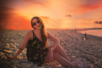 Woman sitting at beach during sunset