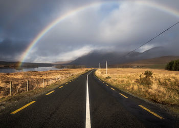 Scenic view of rainbow over road against sky