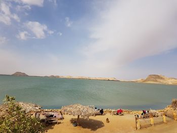 Panoramic view of people on beach against sky