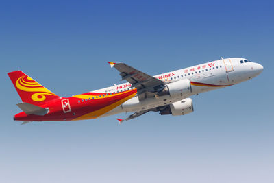 Low angle view of airplane flying against clear blue sky