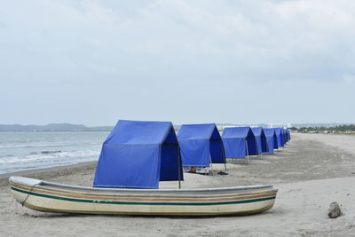 Deck chairs on beach against sky