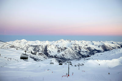 Ski lift on snow covered landscape during sunset