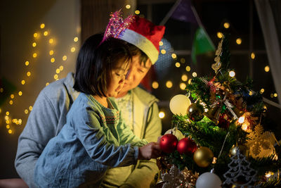 Portrait of woman holding christmas tree at night