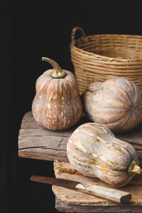 Close-up of pumpkins and basket on table against black background
