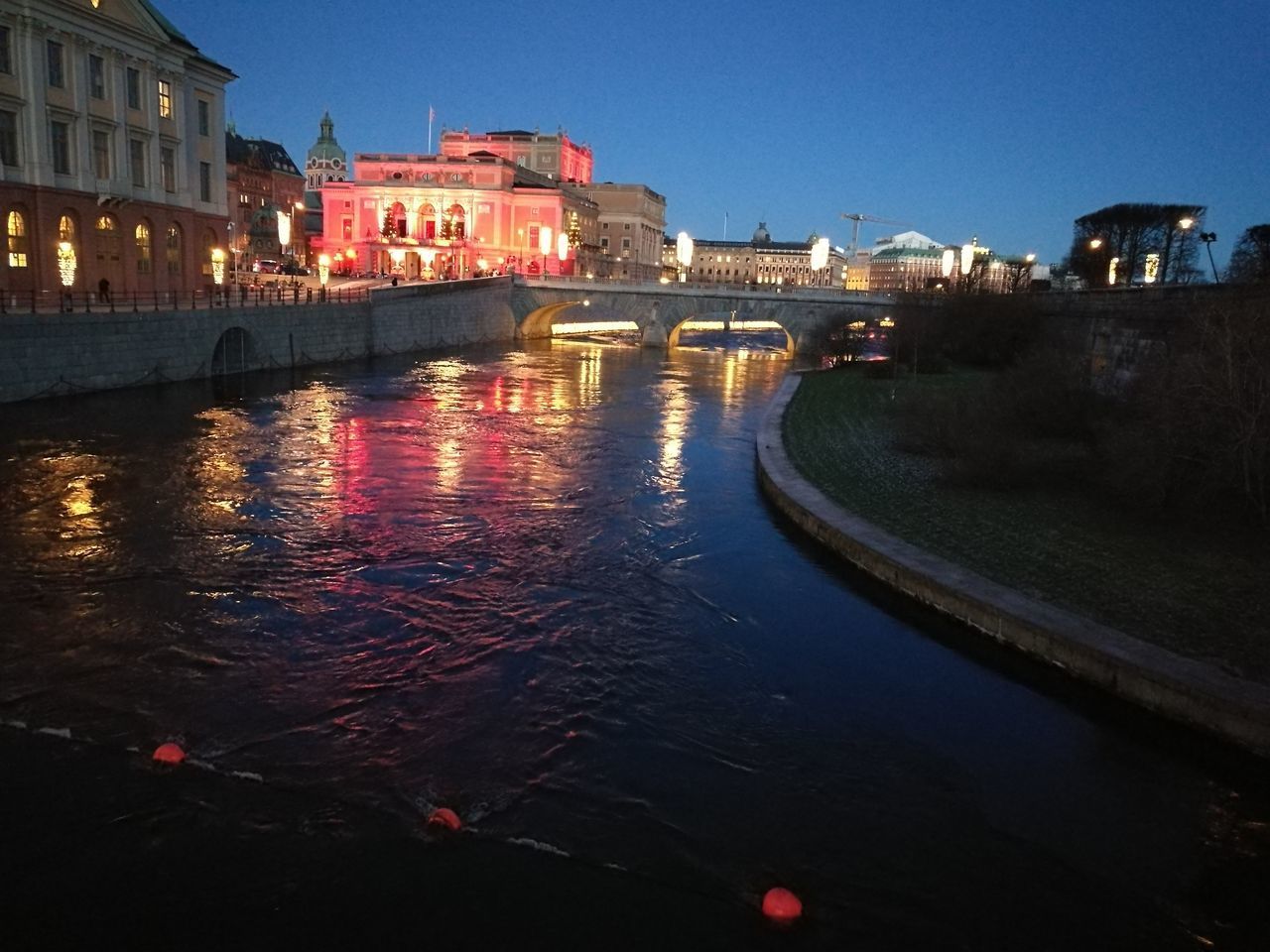 CANAL IN ILLUMINATED CITY AT NIGHT