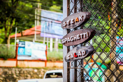 Close-up of information sign on fence