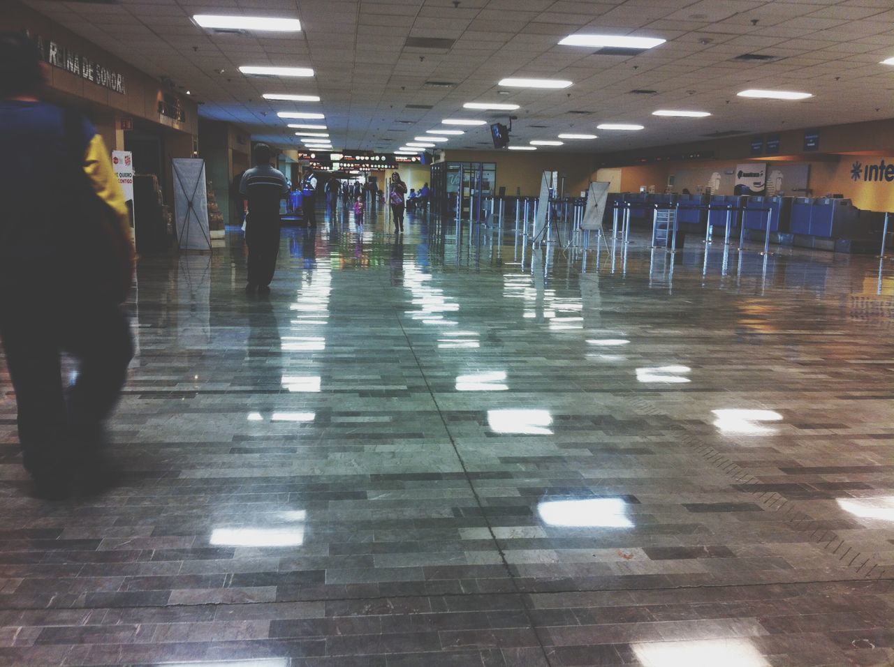 indoors, tiled floor, flooring, illuminated, ceiling, in a row, corridor, architecture, empty, built structure, incidental people, reflection, lighting equipment, the way forward, floor, diminishing perspective, repetition, tile, architectural column