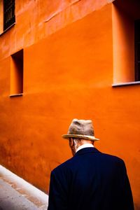 Rear view of man standing against orange wall