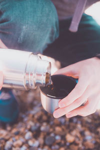 Close-up of person pouring coffee in lid