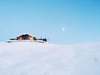 House on snow covered landscape against sky