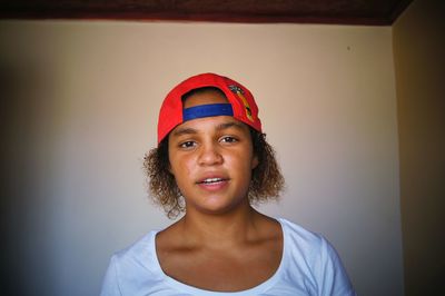 Portrait of young woman wearing cap against wall at home