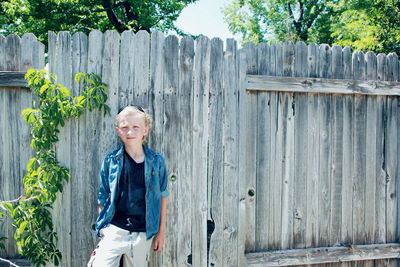 Portrait of smiling boy standing against fence