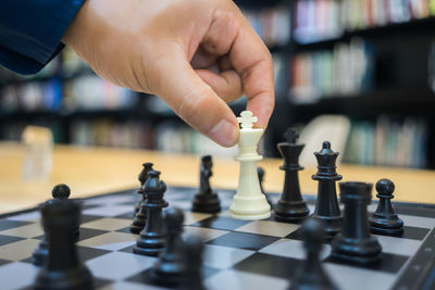 Cropped hand of man playing chess on table in library