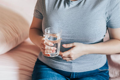 Midsection of woman holding coffee at home