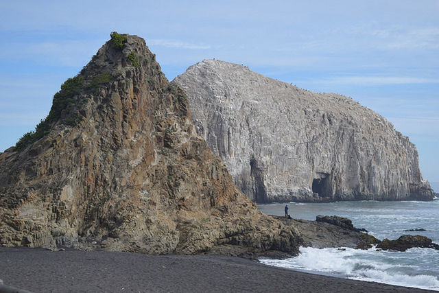 ROCKS BY SEA AGAINST SKY