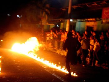 People walking on illuminated street in city at night