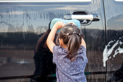 Rear view of girl cleaning car