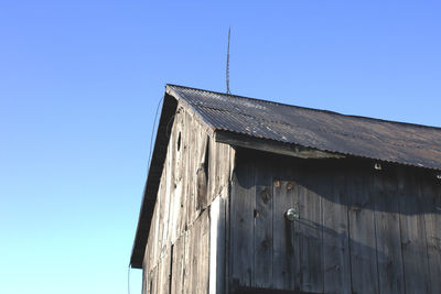 Low angle view of barn against clear blue sky