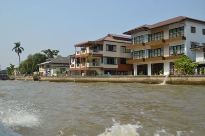 Buildings by sea against clear sky