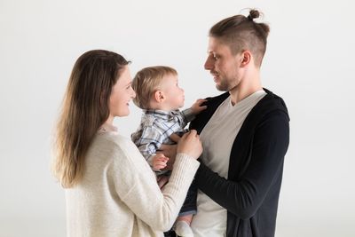 Side view of couple holding hands against white background