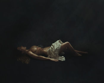 Woman lying down against black background