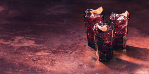 Alcoholic drink with lemon and ice, red lighting, marble table