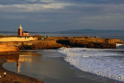 Lighthouse by sea against sky