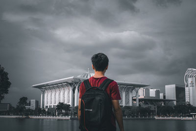 Man standing by buildings against sky