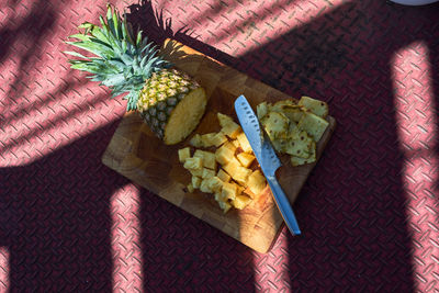 High angle view of chopped pineapple on cutting board over sheet metal