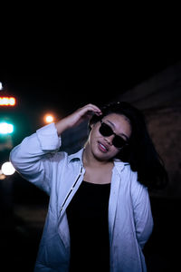Young woman wearing sunglasses against black background