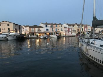 Sailboats moored at harbor against buildings in city