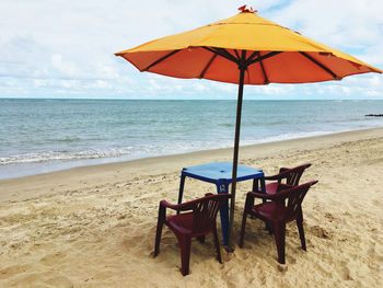 Deck chairs on beach against sky