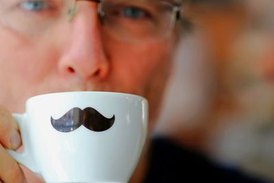 Portrait of man drinking coffee from mustache cup